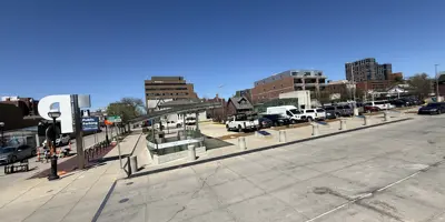 Parking lot site of Library Lane in Ann Arbor with cars parked and blue sky with buildings in the background