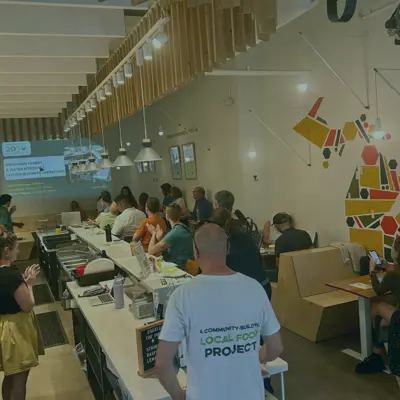 A large group of people sit facing a screen in a restaurant