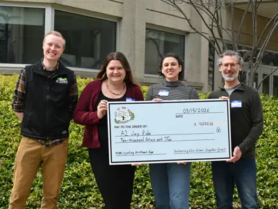 Office of Sustainability and Innovations staff with A2 Joyrides holding a large check, made out to A2 Joyrides. 