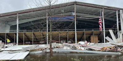 Damage to Veterans Memorial Park Ice Arena building shows the entire wall missing and flooding in the foreground