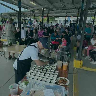 Chef in front of crowd preparing samples for tasting at a festival
